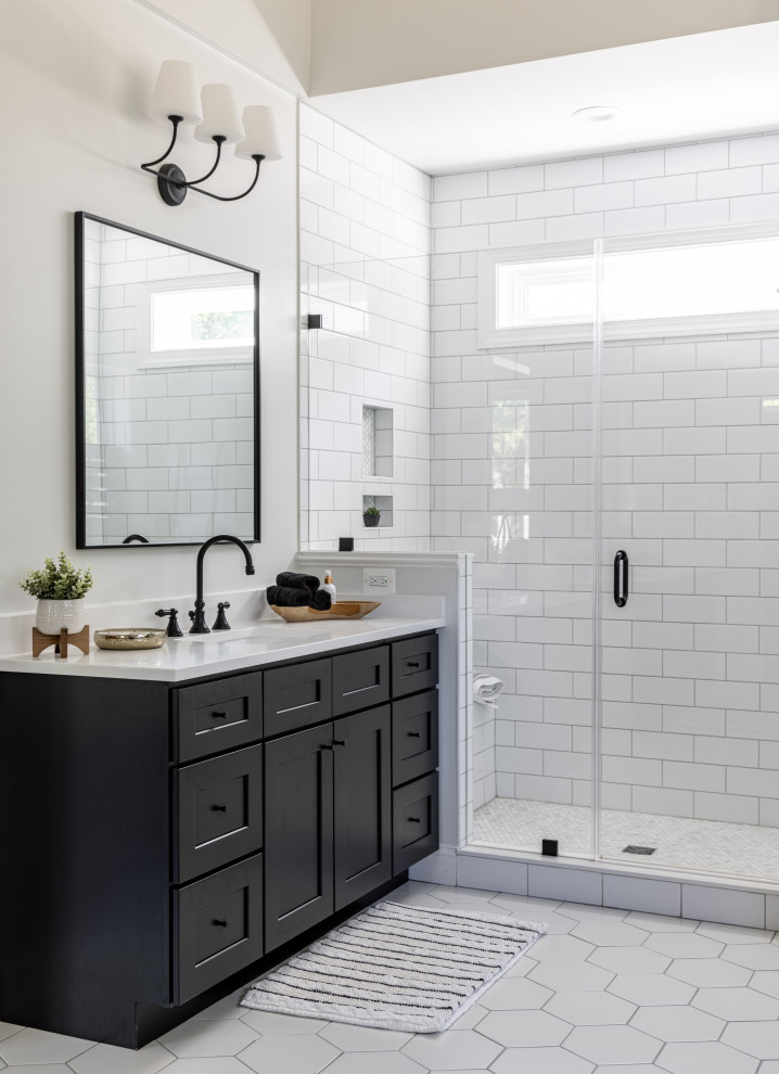 Пример оригинального дизайна: главная ванная комната среднего размера в стиле кантри с фасадами в стиле шейкер, черными фасадами, отдельно стоящей ванной, душем в нише, унитазом-моноблоком, белой плиткой, керамической плиткой, белыми стенами, полом из керамической плитки, врезной раковиной, столешницей из искусственного кварца, белым полом, душем с распашными дверями, белой столешницей, сиденьем для душа, тумбой под две раковины, встроенной тумбой и сводчатым потолком