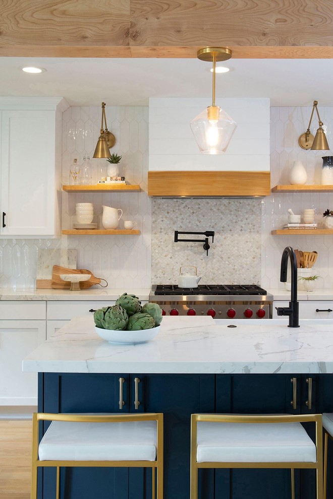 Inspiration for a mid-sized transitional galley open plan kitchen in Denver with a farmhouse sink, shaker cabinets, white cabinets, quartz benchtops, white splashback, ceramic splashback, stainless steel appliances, light hardwood floors, with island, beige floor and white benchtop.