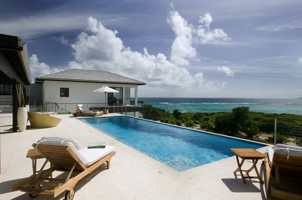 Inspiration for a beach style backyard rectangular infinity pool in Other with a water feature.