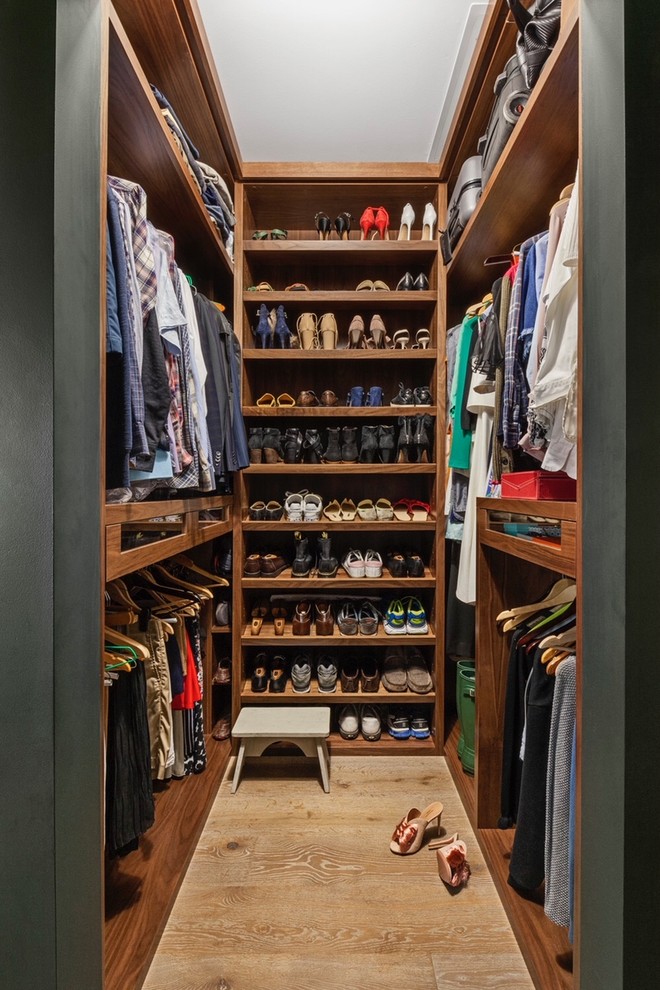 Inspiration for a transitional gender-neutral walk-in wardrobe in New York with open cabinets, medium wood cabinets, light hardwood floors and beige floor.
