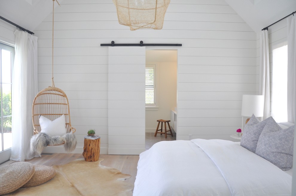 Beach style master bedroom in Other with white walls and light hardwood floors.
