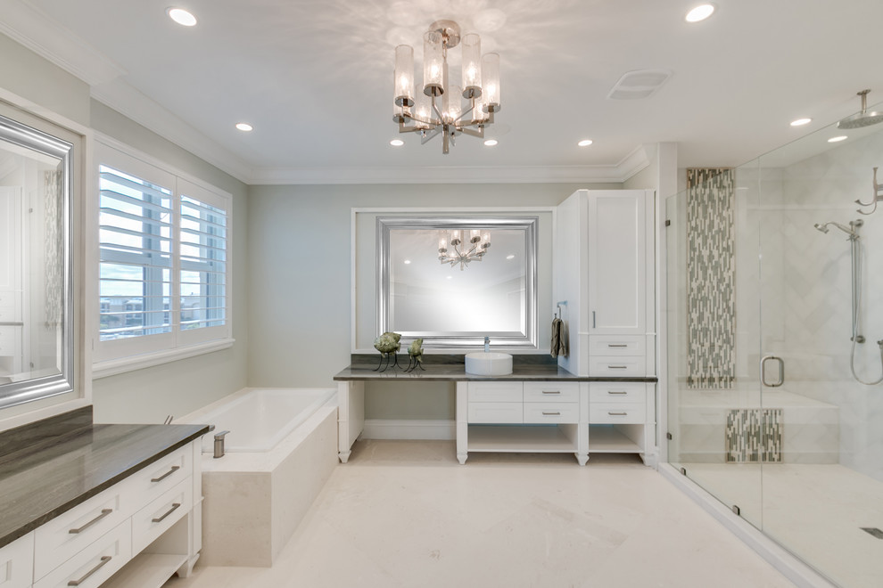 This is an example of a large traditional master wet room bathroom in Miami with recessed-panel cabinets, white cabinets, a hot tub, a two-piece toilet, white tile, marble, green walls, limestone floors, a vessel sink, quartzite benchtops, beige floor, a hinged shower door and green benchtops.