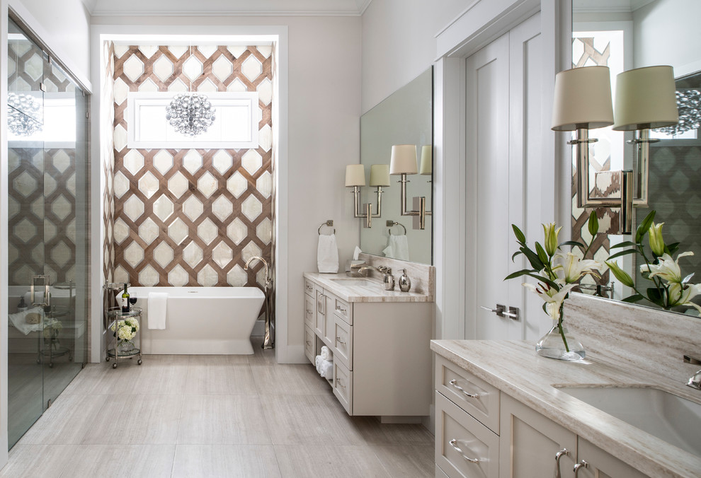 Photo of a large transitional master bathroom in Los Angeles with shaker cabinets, beige cabinets, a freestanding tub, beige walls, an undermount sink, beige benchtops, a curbless shower, a one-piece toilet, beige tile, mosaic tile, marble floors, solid surface benchtops, beige floor and a hinged shower door.