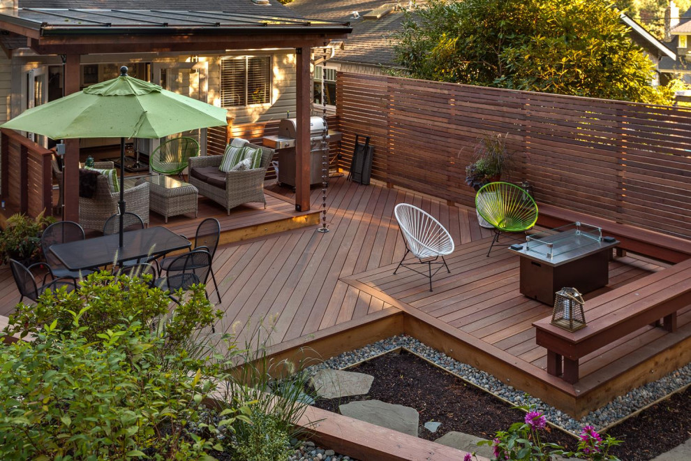 Example of a mid-sized transitional backyard deck design in Calgary with a pergola