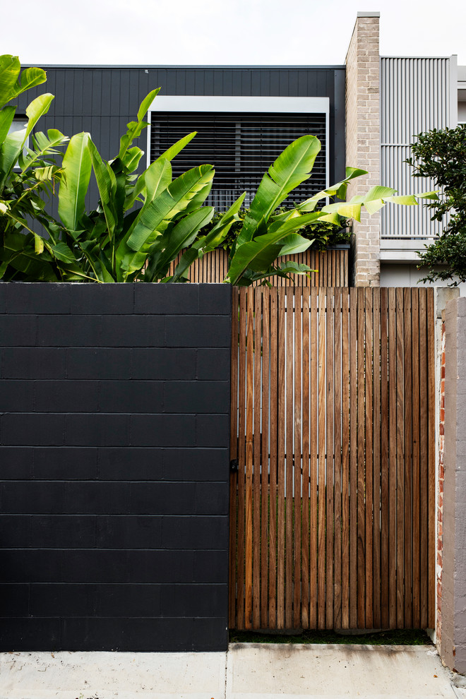 Small tropical backyard full sun garden in Sydney with a retaining wall and decking.