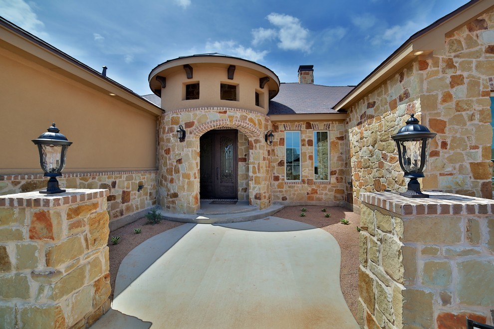 Inspiration for a mid-sized mediterranean beige one-story stone exterior home remodel in Dallas with a hip roof
