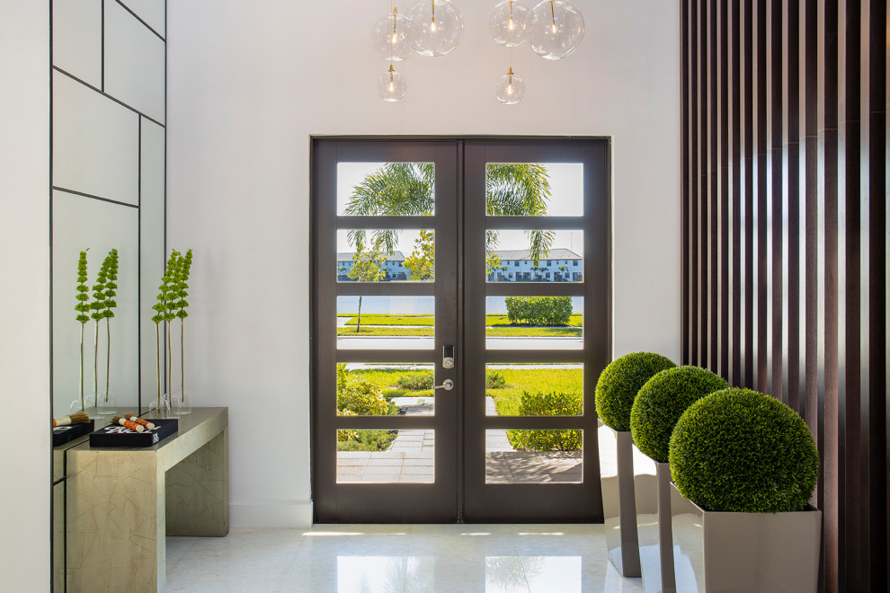 This is an example of a large modern foyer in Miami with white walls, marble floors, a double front door, a white front door and white floor.