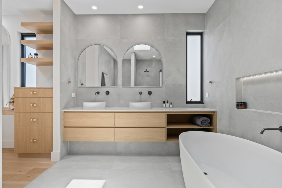 Foto på ett stort skandinaviskt vit en-suite badrum, med möbel-liknande, beige skåp, ett fristående badkar, en dubbeldusch, grå kakel, porslinskakel, grå väggar, klinkergolv i porslin, ett integrerad handfat, granitbänkskiva, grått golv och med dusch som är öppen