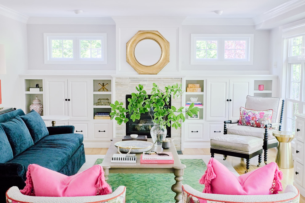 Photo of a mid-sized transitional living room in Providence with light hardwood floors, a standard fireplace, a library, a tile fireplace surround and grey walls.