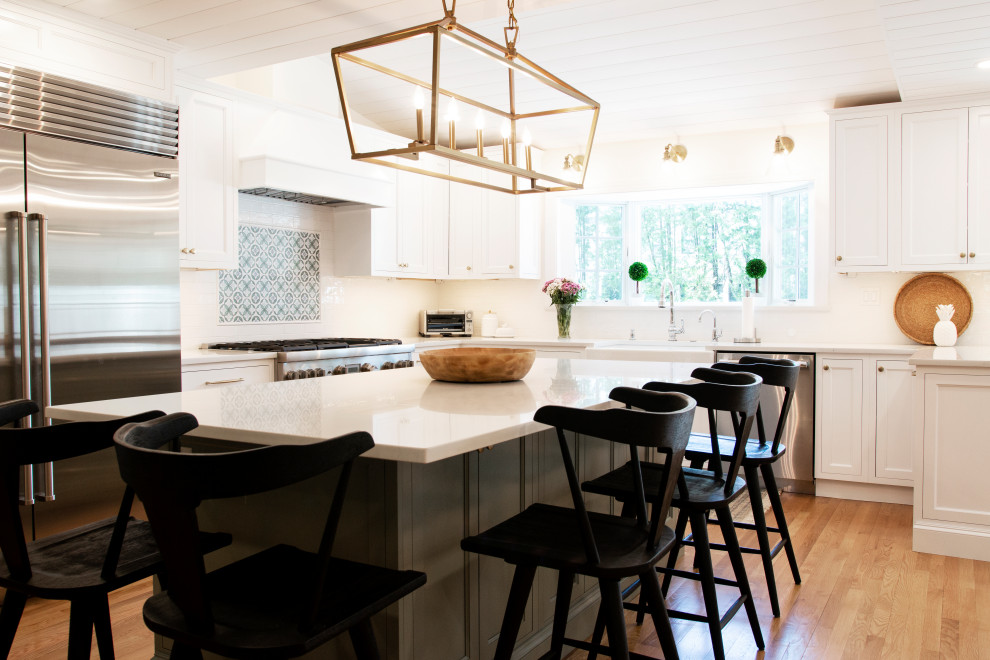 Expansive traditional u-shaped eat-in kitchen in Boston with a farmhouse sink, flat-panel cabinets, green cabinets, quartz benchtops, green splashback, marble splashback, stainless steel appliances, light hardwood floors, multiple islands, brown floor, white benchtop and timber.