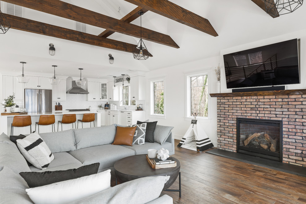 Photo of a transitional open concept living room in New York with white walls, dark hardwood floors, a standard fireplace, a brick fireplace surround and brown floor.