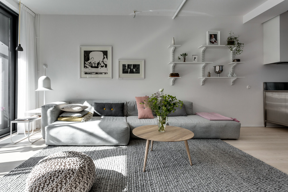 This is an example of a mid-sized scandinavian formal open concept living room in Stockholm with white walls, light hardwood floors, no fireplace and no tv.