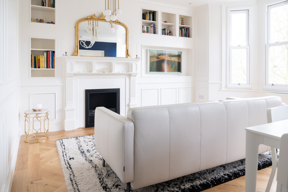 Inspiration for a mid-sized modern open concept living room in London with a library, white walls, light hardwood floors, a standard fireplace, a stone fireplace surround, a wall-mounted tv and brown floor.