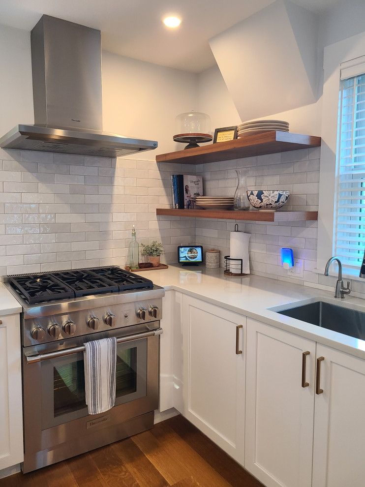 Example of a large transitional u-shaped medium tone wood floor and brown floor eat-in kitchen design in Boston with an undermount sink, recessed-panel cabinets, white cabinets, white backsplash, subway tile backsplash, stainless steel appliances, an island and white countertops