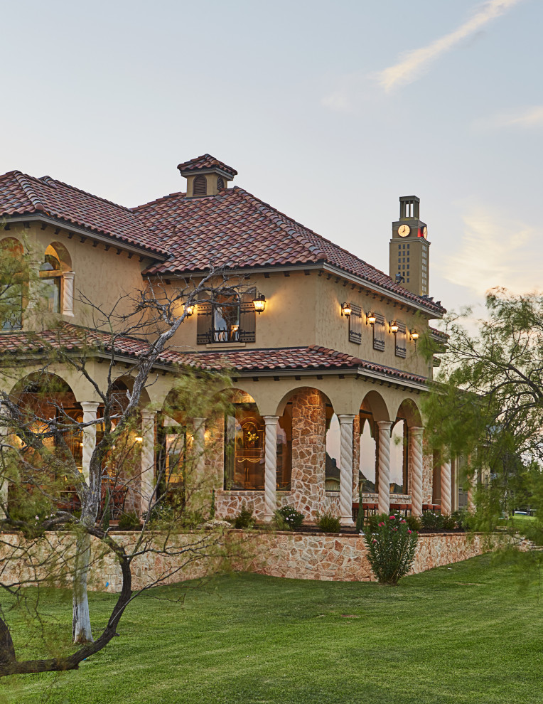 Photo of a mediterranean two-storey beige house exterior in Dallas with a tile roof.