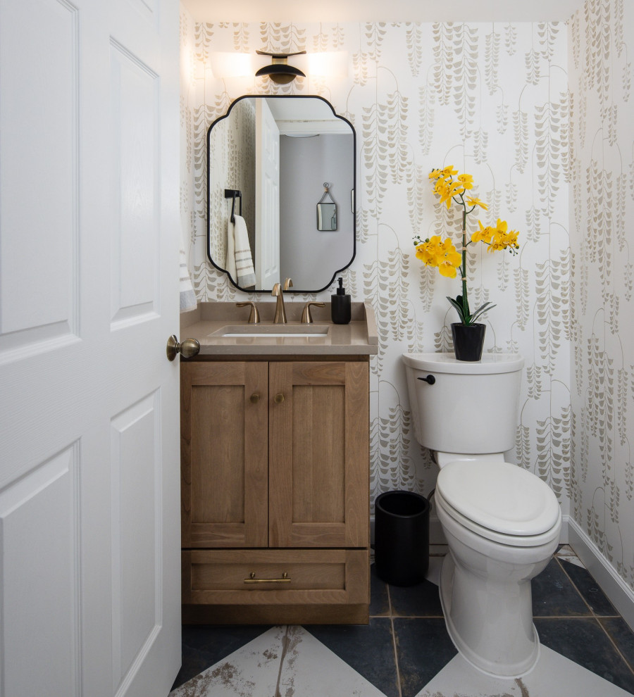 Example of a transitional white tile black floor and wallpaper powder room design in DC Metro with shaker cabinets, medium tone wood cabinets, white walls, an undermount sink, beige countertops and a freestanding vanity