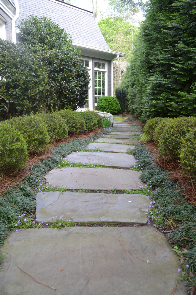 This is an example of a traditional backyard shaded formal garden for spring in Atlanta with a garden path and natural stone pavers.