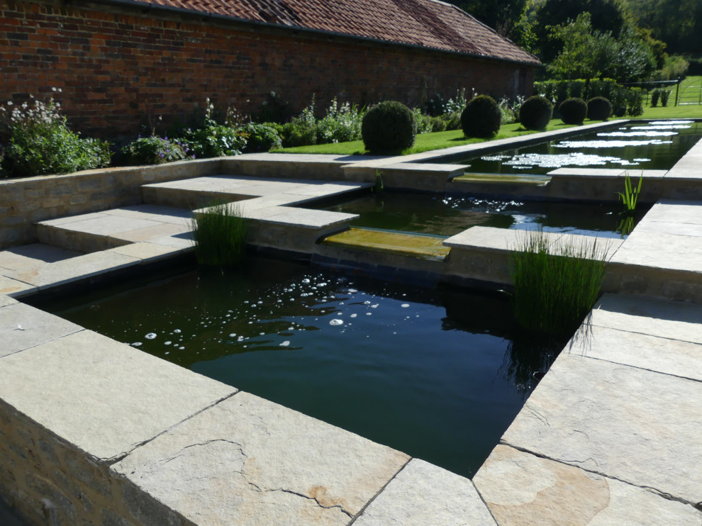 Geometrischer, Großer Moderner Gartenwasserfall hinter dem Haus mit direkter Sonneneinstrahlung und Natursteinplatten in Wiltshire