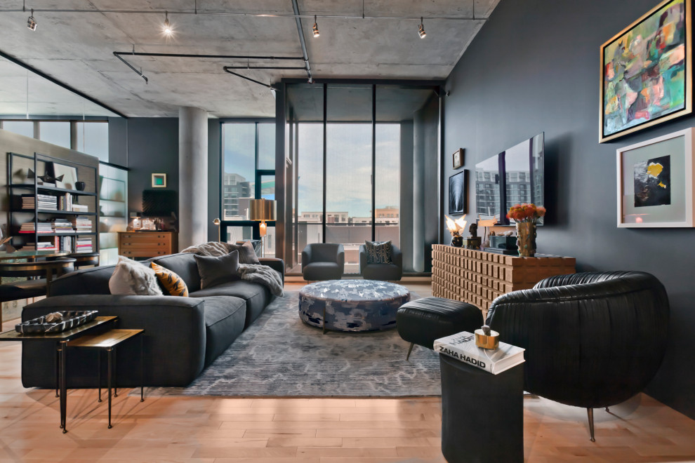 This is an example of a contemporary open concept living room in Minneapolis with black walls, medium hardwood floors, no fireplace, a wall-mounted tv and brown floor.