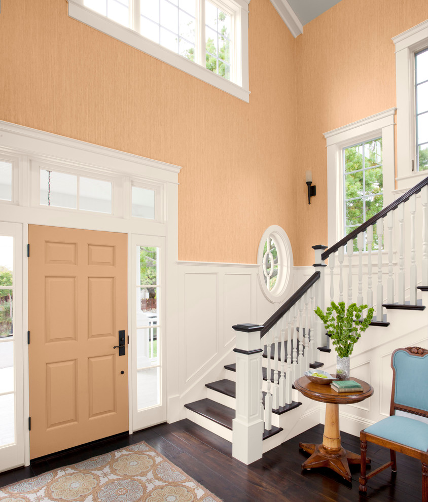 Photo of a large transitional foyer in Charlotte with orange walls, dark hardwood floors, a single front door and an orange front door.