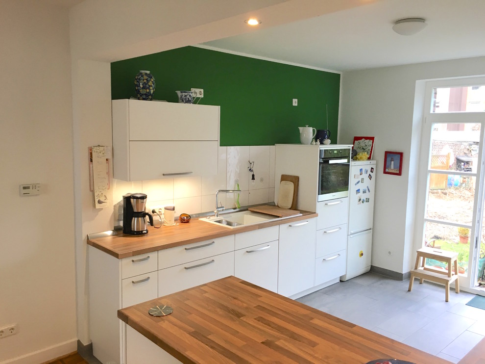 Mid-sized scandinavian u-shaped eat-in kitchen in Essen with white cabinets, wood benchtops, white splashback, ceramic splashback, ceramic floors and a peninsula.