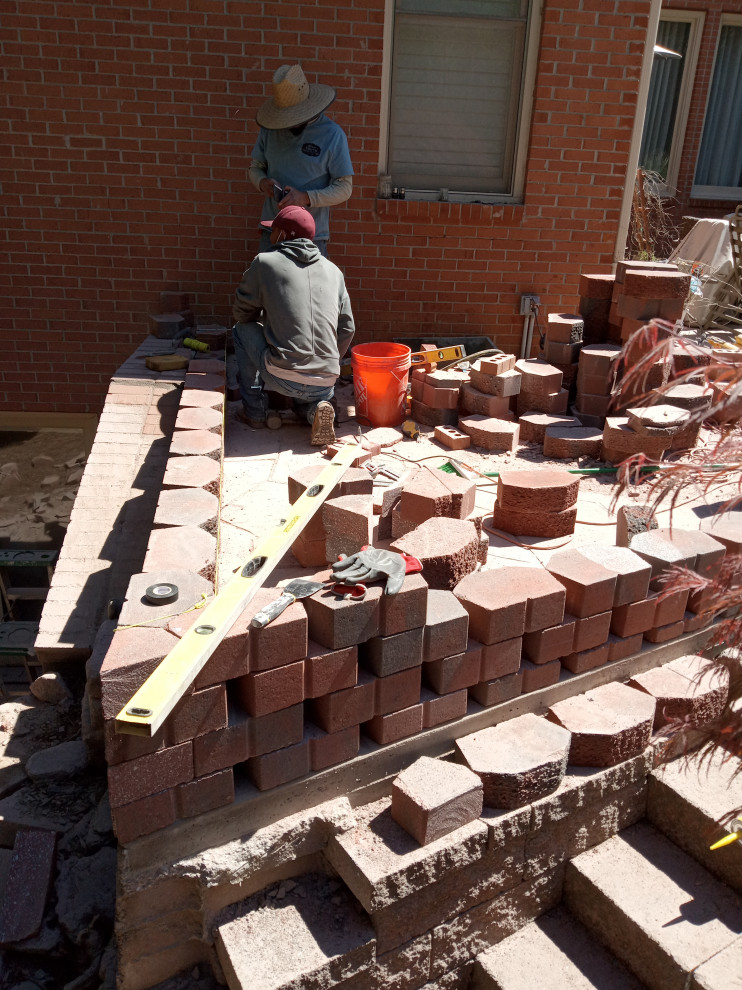 Photo of a large craftsman privacy, rock and full sun backyard concrete paver retaining wall landscape for summer.