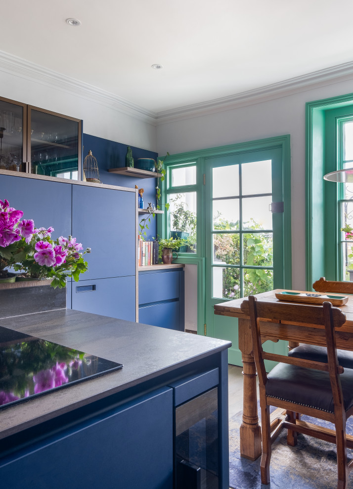 На фото: маленькая отдельная, п-образная кухня в стиле фьюжн с накладной мойкой, плоскими фасадами, синими фасадами, столешницей из акрилового камня, черной техникой и серой столешницей для на участке и в саду