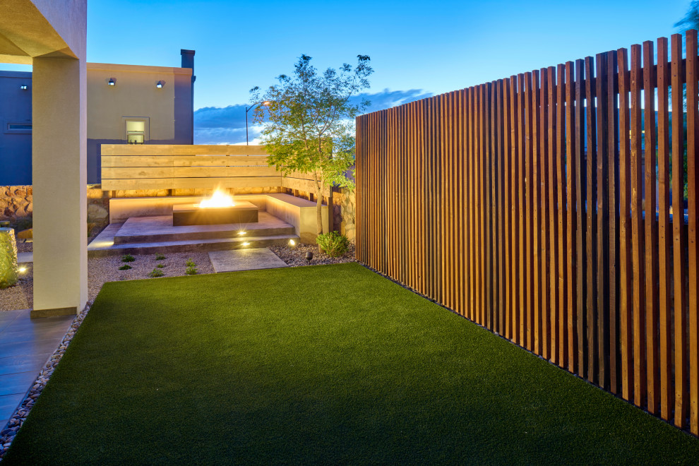 Cette image montre un petit xéropaysage arrière design avec un foyer extérieur, des pavés en béton et une clôture en bois.