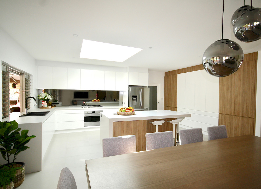 Inspiration for a large modern l-shaped eat-in kitchen in Sydney with a drop-in sink, flat-panel cabinets, white cabinets, quartz benchtops, grey splashback, mirror splashback, stainless steel appliances, ceramic floors, with island, grey floor and grey benchtop.