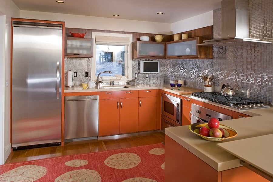 Photo of a mid-sized u-shaped eat-in kitchen in Portland Maine with an undermount sink, glass-front cabinets, orange cabinets and stainless steel appliances.