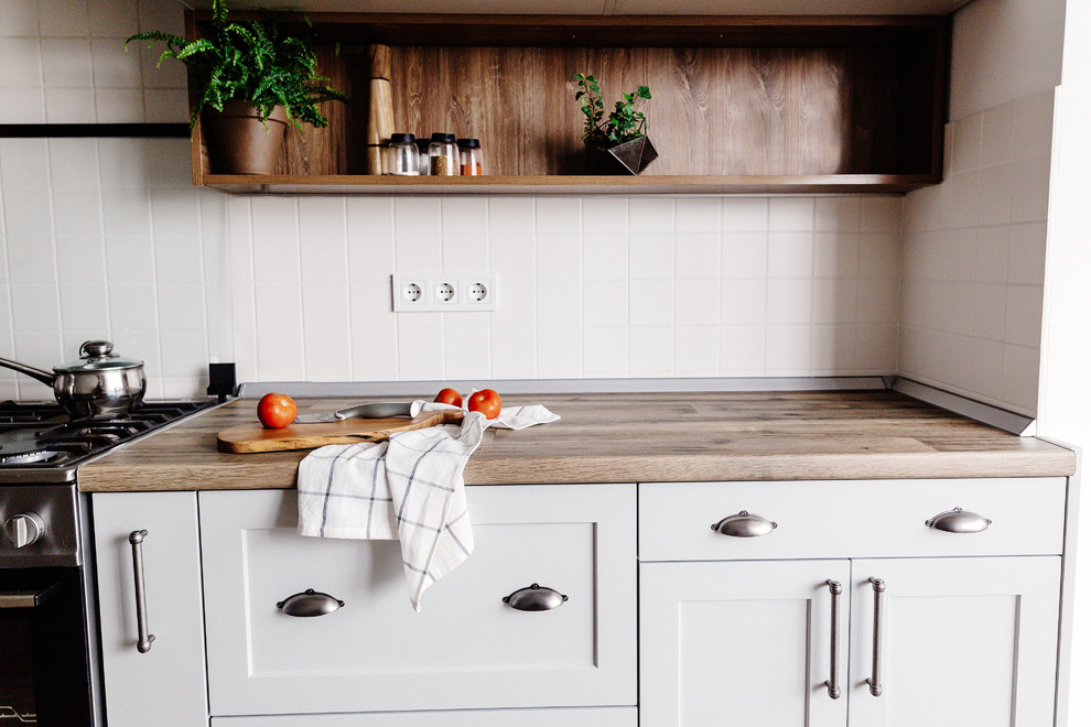 Eat-in kitchen - mid-sized transitional u-shaped dark wood floor and brown floor eat-in kitchen idea in DC Metro with a drop-in sink, recessed-panel cabinets, white cabinets, wood countertops, white backsplash, ceramic backsplash, stainless steel appliances, a peninsula and brown countertops
