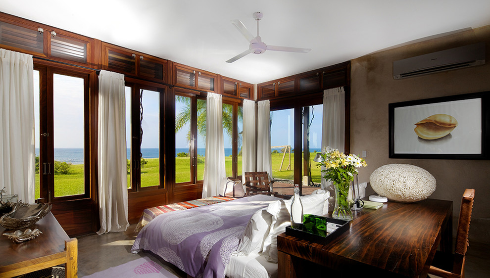Design ideas for a tropical master bedroom in New York with brown walls and concrete floors.