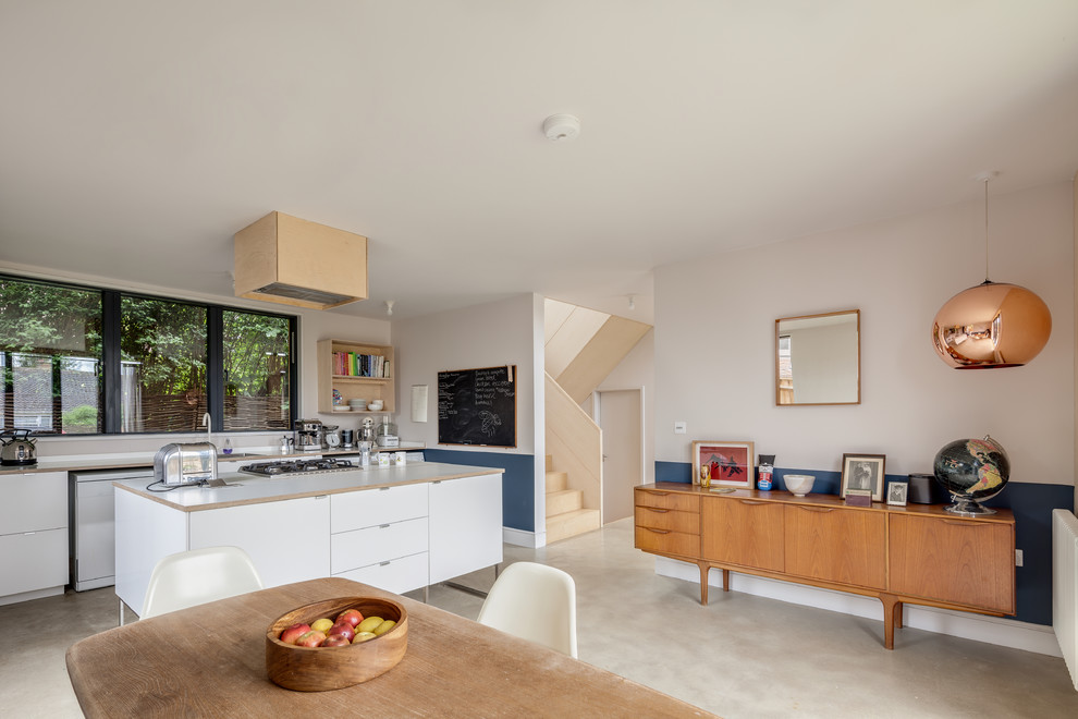 This is an example of a mid-sized scandinavian single-wall eat-in kitchen in Buckinghamshire with flat-panel cabinets, white cabinets, wood benchtops, concrete floors, with island, grey floor and beige benchtop.