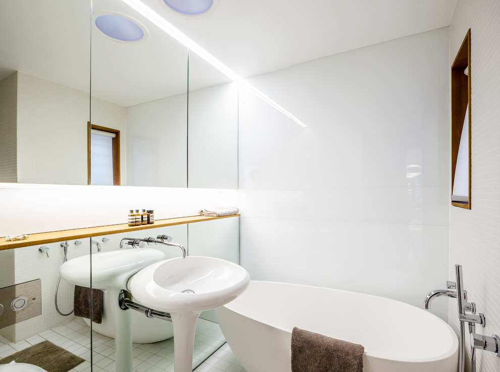 Contemporary bathroom in Sydney with a drop-in tub, white tile, white walls and a pedestal sink.