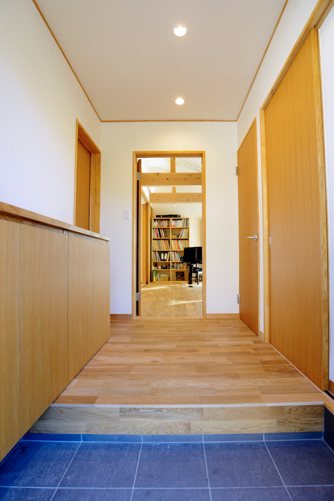 Photo of a medium sized world-inspired hallway in Other with white walls, light hardwood flooring, a single front door, a dark wood front door, beige floors, a wallpapered ceiling and wallpapered walls.