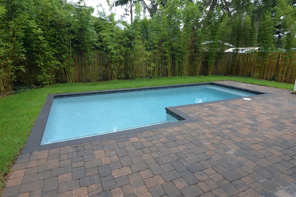 Mid-sized country backyard l-shaped lap pool in Orlando with brick pavers.