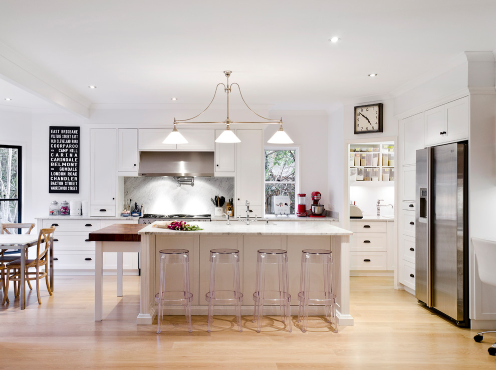 This is an example of a transitional l-shaped eat-in kitchen in Brisbane with shaker cabinets, white cabinets, grey splashback, stainless steel appliances, light hardwood floors, with island, beige floor and grey benchtop.