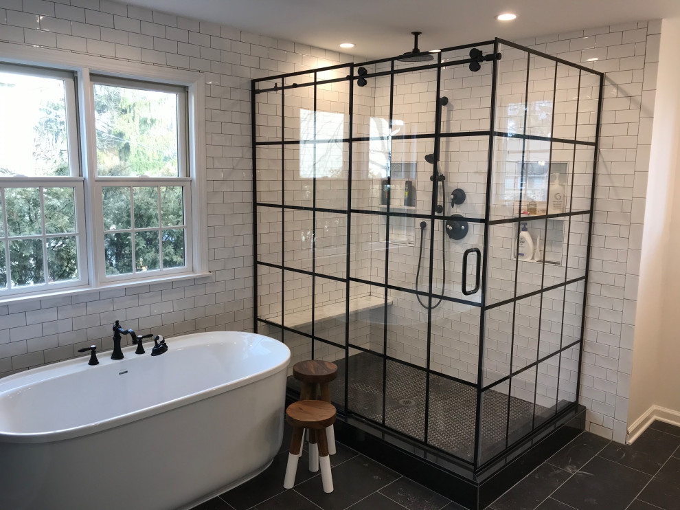 Photo of a mid-sized master bathroom in New York with furniture-like cabinets, distressed cabinets, a freestanding tub, a corner shower, a one-piece toilet, white tile, white walls, ceramic floors, an integrated sink, quartzite benchtops, black floor and white benchtops.