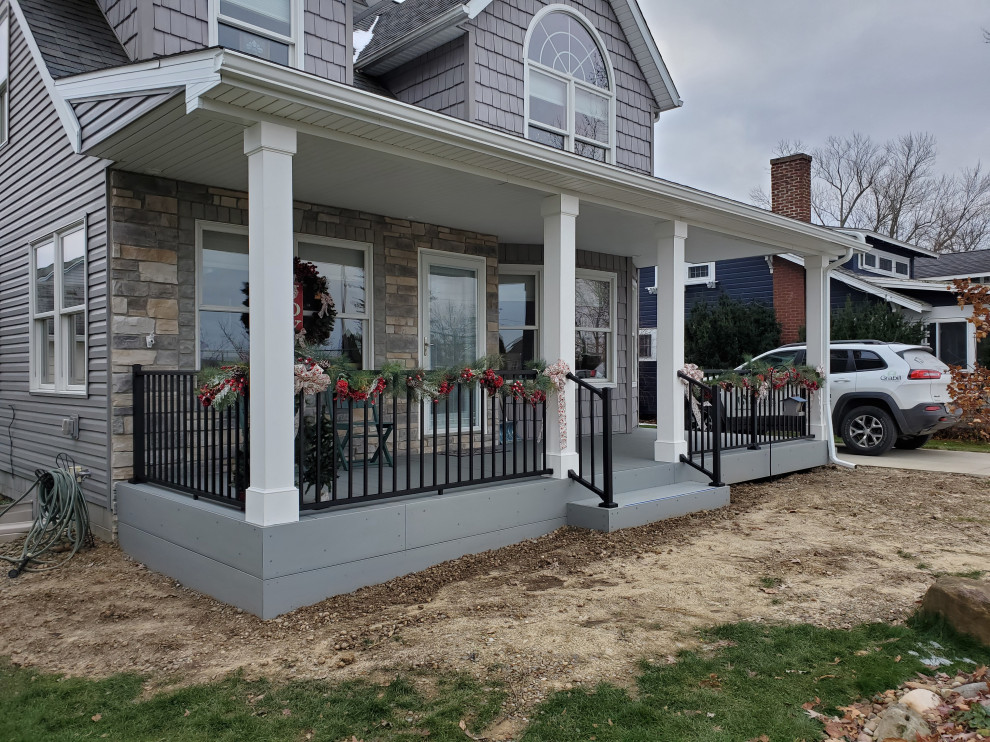 Cette image montre un porche d'entrée de maison avant craftsman de taille moyenne avec jupe de finition, une terrasse en bois, une extension de toiture et un garde-corps en métal.