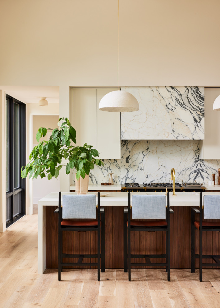 Inspiration for an expansive contemporary u-shaped open plan kitchen in Grand Rapids with an undermount sink, flat-panel cabinets, medium wood cabinets, stone slab splashback, panelled appliances, light hardwood floors, with island, white benchtop and vaulted.