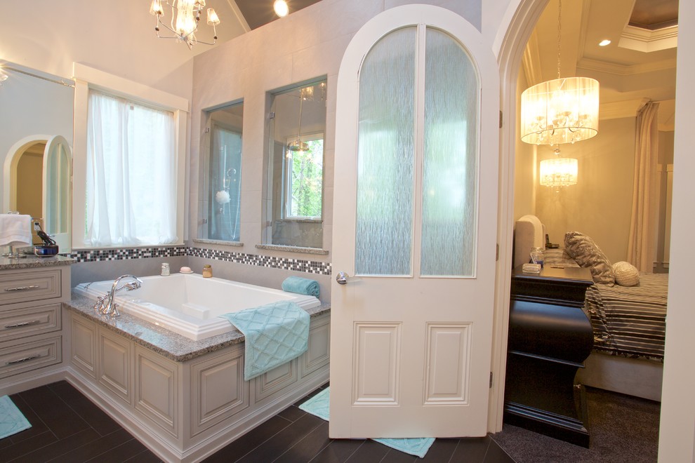 Huge transitional master beige tile and ceramic tile dark wood floor corner bathtub photo with an undermount sink, beaded inset cabinets, gray cabinets, granite countertops and beige walls