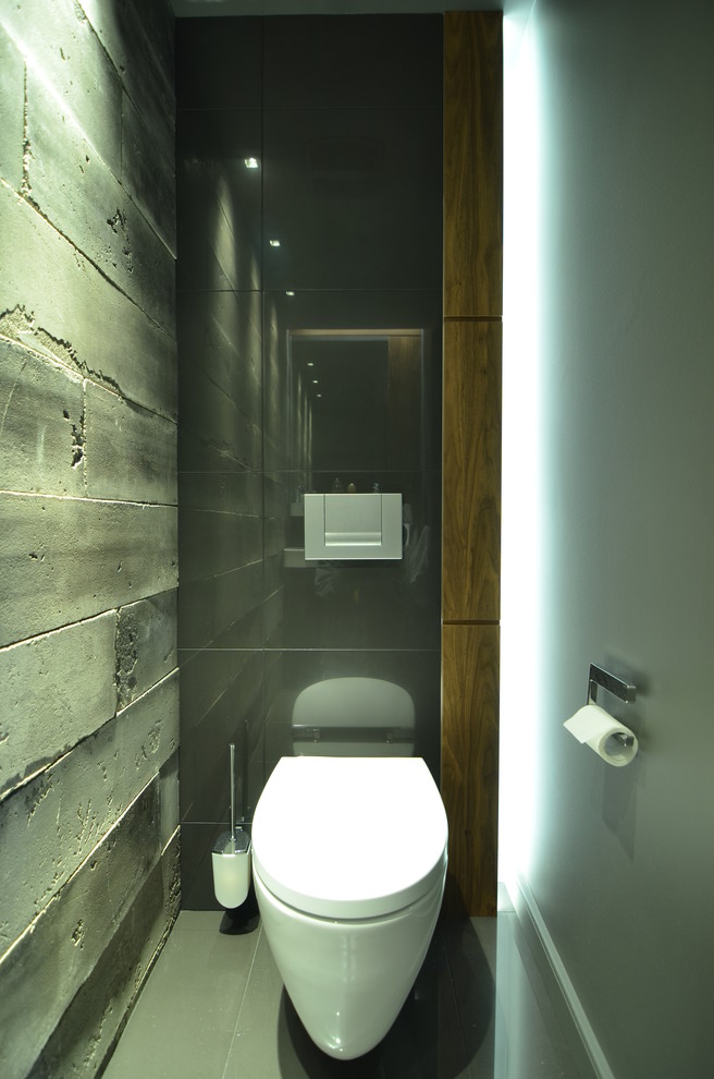 Inspiration for a small industrial powder room in Montreal with dark wood cabinets, a wall-mount toilet, porcelain tile, grey walls, porcelain floors and gray tile.