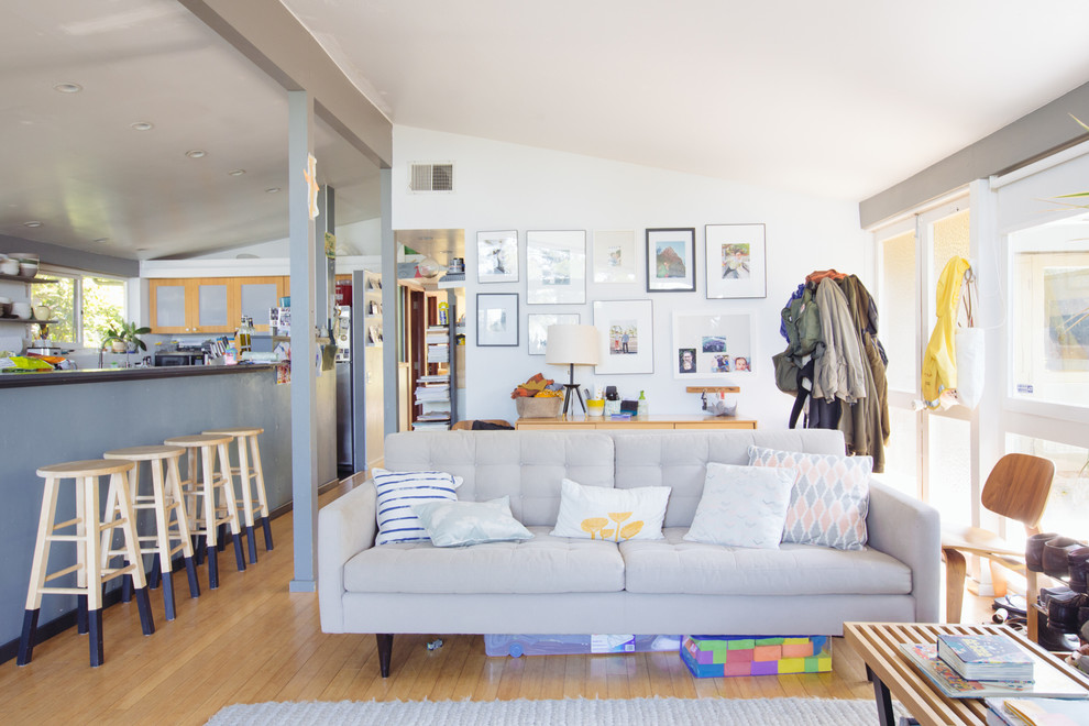 This is an example of a midcentury open concept living room in San Francisco with white walls and medium hardwood floors.