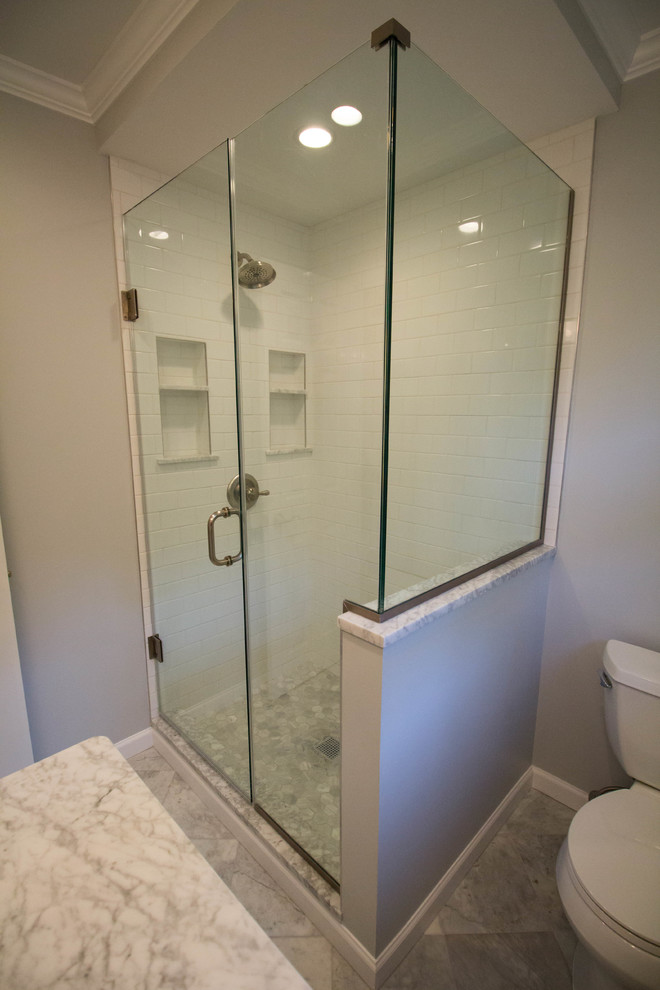 Corner shower - small transitional master white tile and ceramic tile marble floor and gray floor corner shower idea in Newark with shaker cabinets, white cabinets, a two-piece toilet, gray walls, an undermount sink, marble countertops and a hinged shower door