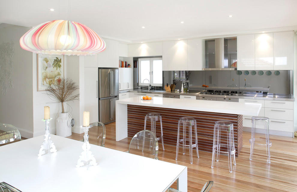 Photo of a midcentury eat-in kitchen in Sydney with flat-panel cabinets, white cabinets, quartz benchtops and stainless steel appliances.
