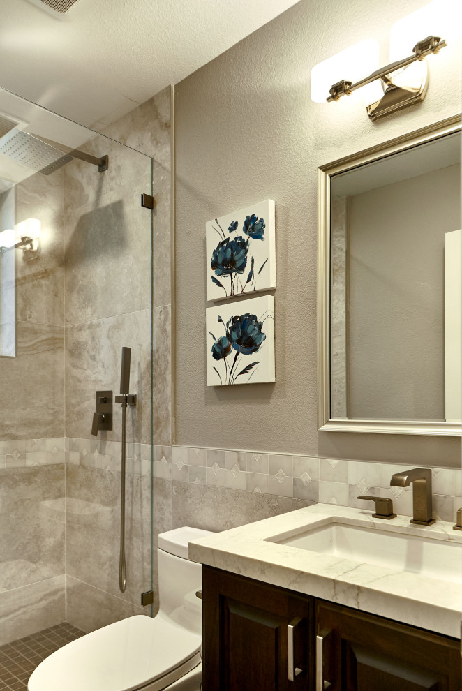 Идея дизайна: маленькая ванная комната в стиле неоклассика (современная классика) с фасадами с выступающей филенкой, коричневыми фасадами, ванной в нише, душем над ванной, унитазом-моноблоком, бежевой плиткой, керамогранитной плиткой, серыми стенами, полом из керамогранита, душевой кабиной, врезной раковиной, столешницей из искусственного кварца, серым полом, душем с распашными дверями, серой столешницей, тумбой под одну раковину и встроенной тумбой для на участке и в саду