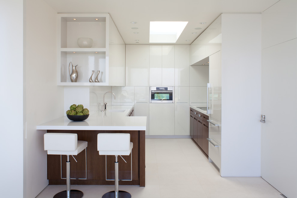 This is an example of a small contemporary galley eat-in kitchen in Los Angeles with flat-panel cabinets, white cabinets and panelled appliances.