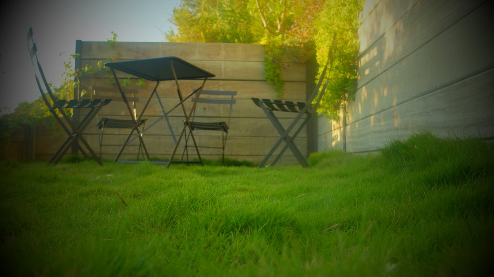 Inspiration pour un jardin design avec un mur de soutènement et une terrasse en bois.