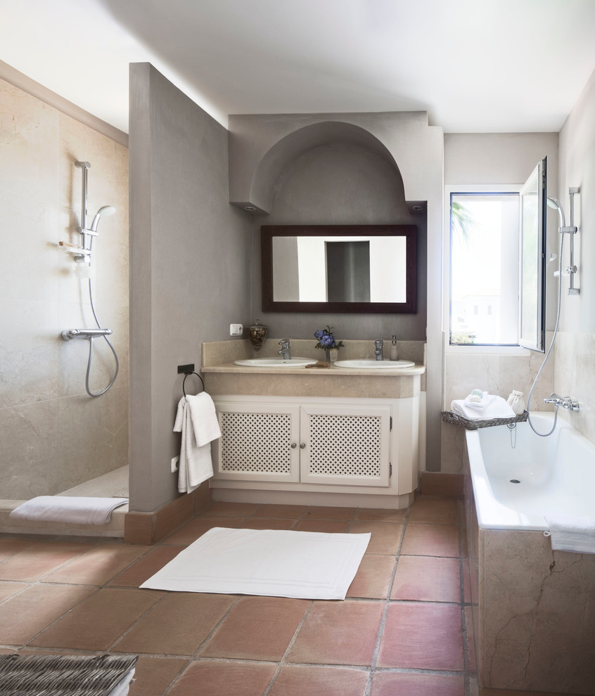 Inspiration for a mid-sized country master bathroom in Madrid with a drop-in sink, white cabinets, an open shower, terra-cotta floors, a drop-in tub, grey walls, marble benchtops and an open shower.