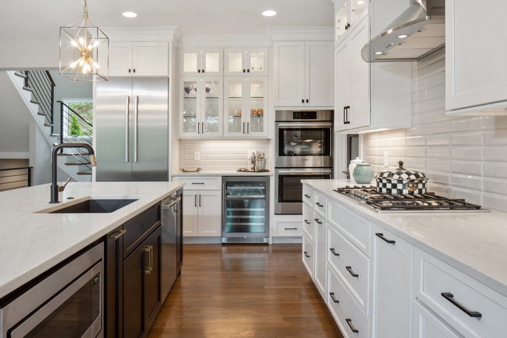 Kitchen - transitional l-shaped marble floor and brown floor kitchen idea with an undermount sink, recessed-panel cabinets, white cabinets, white backsplash, stainless steel appliances, an island and white countertops